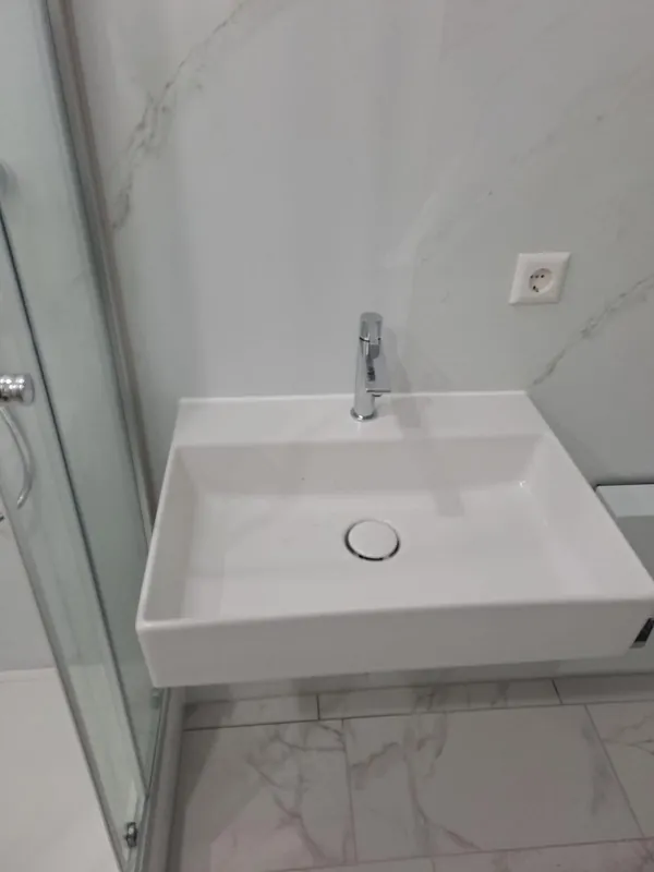 Eckiges Waschbecken neben der Glas-Duschkabine