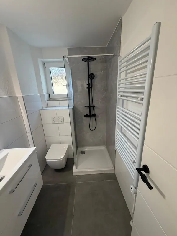 Duschbad mit Handtuchheizkörper und schwarzer Regendusche